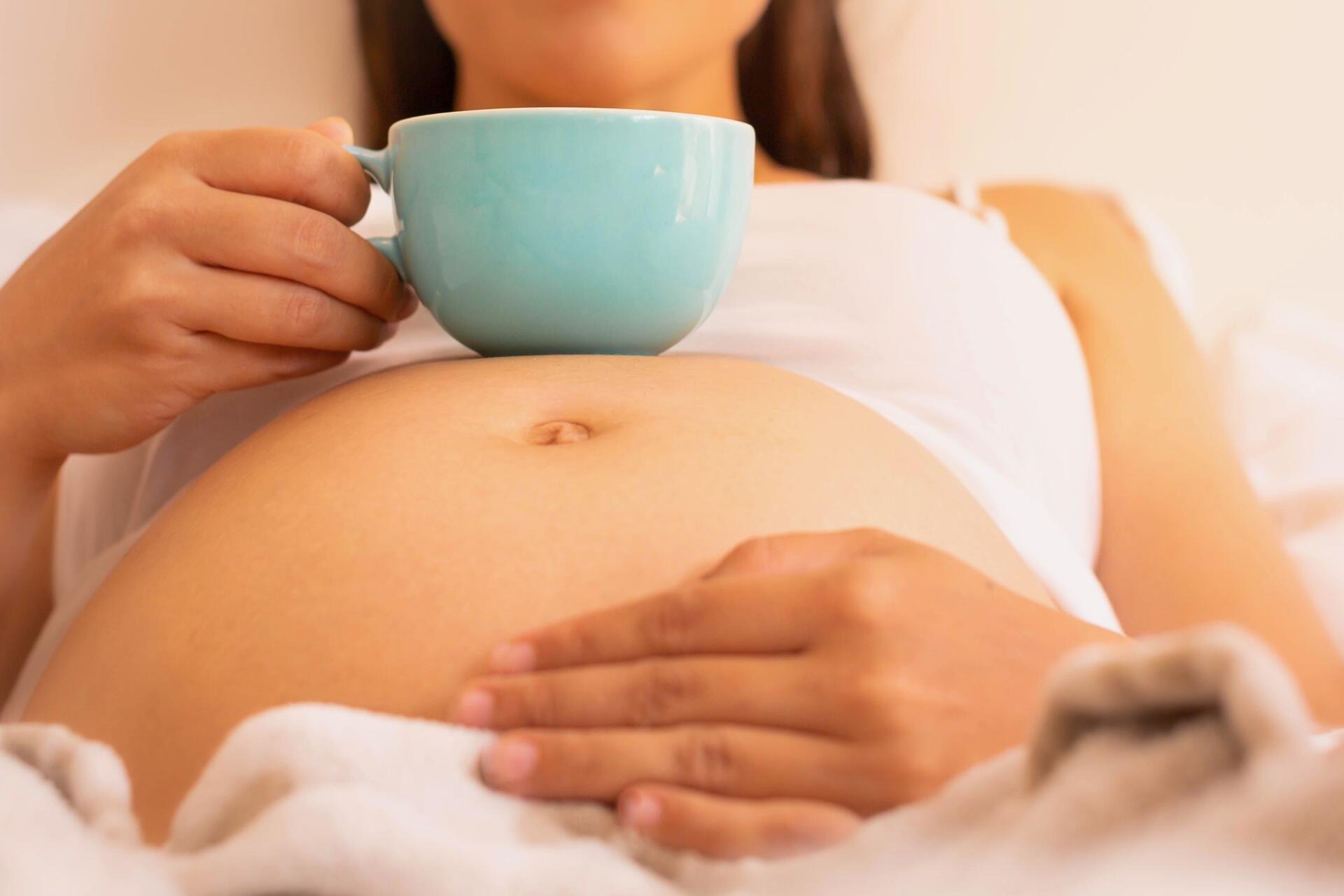 Babybauch mit Tasse