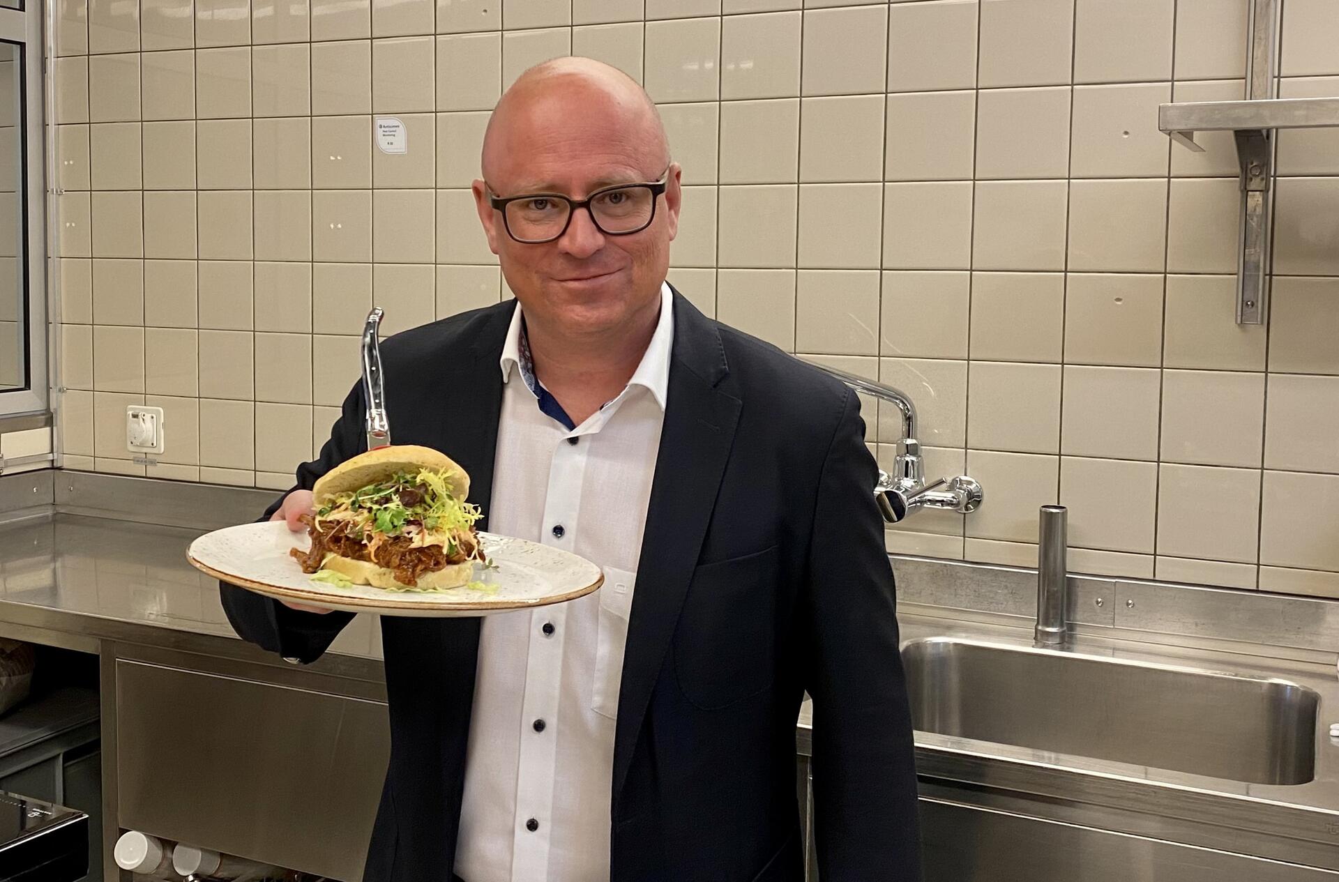 Daniel Gehriger präsentiert einen Burger. 